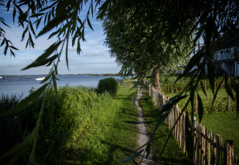 Sendero junto al césped verde con vista al lago desde una casa flotante en Offingawier, Frisia, Países Bajos.