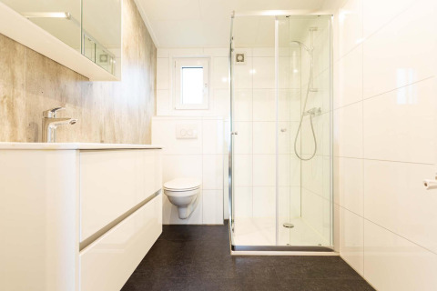 Baño moderno y luminoso con ducha de vidrio y sanitario suspendido en Nature Lodge Wellness, Park Westerkogge.