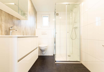 Baño moderno y luminoso con ducha de vidrio y sanitario suspendido en Nature Lodge Wellness, Park Westerkogge.