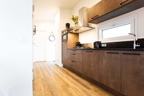 Moderne keuken in Nature Lodge Wellness (Spa) aan Park Westerkogge in Nederland met houten vloer en stijlvolle kastjes.