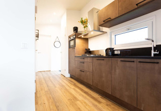 Moderne keuken in Nature Lodge Wellness (Spa) aan Park Westerkogge in Nederland met houten vloer en stijlvolle kastjes.