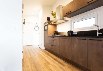 Moderne keuken in Nature Lodge Wellness (Spa) aan Park Westerkogge in Nederland met houten vloer en stijlvolle kastjes.