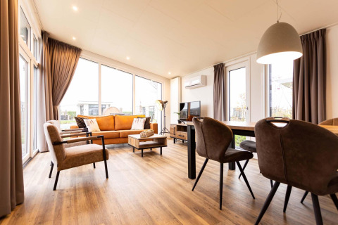 Heldere, moderne woonkamer in Nature Lodge Wellness (Spa) bij Park Westerkogge, Nederland, met grote ramen.
