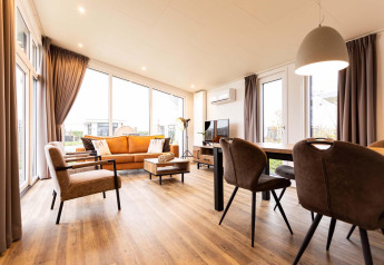 Helles, modernes Wohnzimmer in der Nature Lodge Wellness (Spa) im Park Westerkogge, Niederlande, mit großen Fenstern.