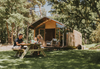 Familie nyder udendørs picnic foran en moderne Wikkelhouse-lodge ved Beerze Bulten i Holland.