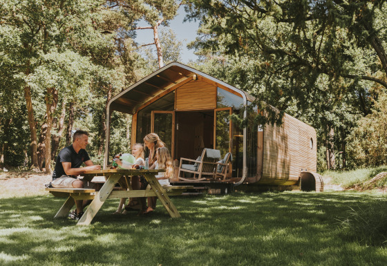 Famille pique-niquant devant un lodge Wikkelhouse moderne à Beerze Bulten, aux Pays-Bas, dans la nature.