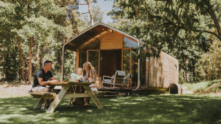 Familia disfruta de un picnic al aire libre frente a la moderna Wikkelhouse en Beerze Bulten, Países Bajos.