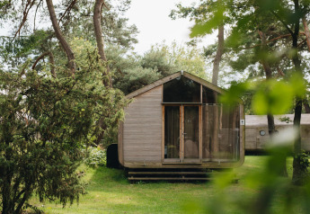 Vooraanzicht van de Wikkelhouse lodge bij Beerze Bulten in Nederland, omringd door bomen en gras.