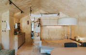 Interieur van de houten Wikkelhouse-lodge bij Beerze Bulten in Nederland met een hoogslaper en kind.