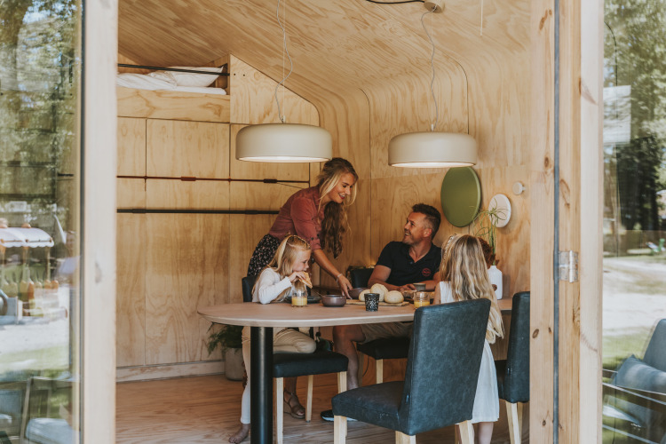 Familia compartiendo una comida en una cabaña de madera en Wikkelhouse, Beerze Bulten, Países Bajos.