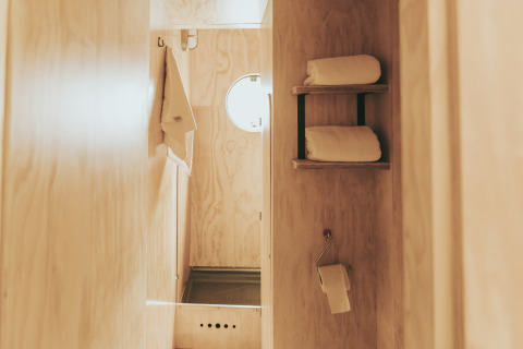 Salle de bain minimaliste au Wikkelhouse de Beerze Bulten (Pays-Bas), intérieur bois et serviettes.