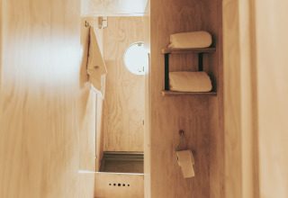 Baño minimalista en Wikkelhouse, Beerze Bulten (Países Bajos), con interior de madera y toallas.