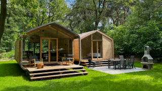 Twee moderne houten huisjes met terrassen bij Wikkelhouse Duo, Beerze Bulten, Nederland, tussen het groen.