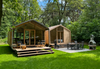 Due rifugi di legno moderni con terrazze al Wikkelhouse Duo, Beerze Bulten, Paesi Bassi, immersi nel verde.