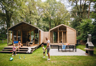 Famiglia che gioca davanti al Wikkelhouse Duo lodge a Beerze Bulten, circondata da alberi nei Paesi Bassi.