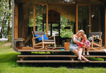 Moeder en kind zitten op de trappen van hun Wikkelhouse Duo lodge in Beerze Bulten, Nederland.
