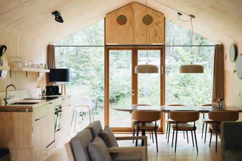 Moderne interiør af Wikkelhouse Duo-lodge ved Beerze Bulten i Holland med træmøbler og stort vindue.