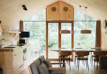 Interior moderno de la Wikkelhouse Duo en Beerze Bulten, Países Bajos, con muebles de madera y grandes ventanales.