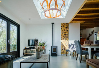 Moderne stue i Nature House, Buitengoed Ruysbos, Holland, med ovenlys, trævæg og træmøbler.