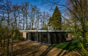 Casa de campo en Buitengoed Ruysbos, Países Bajos, rodeada de árboles y naturaleza, cielo despejado.