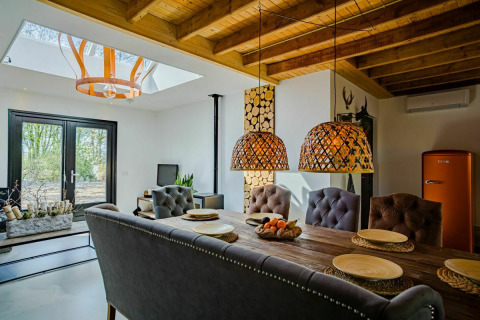 Interiør af Nature House lodge ved Buitengoed Ruysbos i Holland med rustik spiseplads og store lamper.