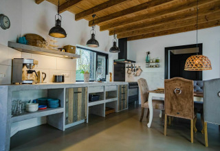 Cocina moderna y acogedora en Nature House, Buitengoed Ruysbos, Países Bajos, con techo de madera y comedor.