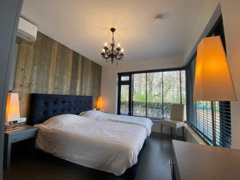 Dormitorio moderno en Nature House, Buitengoed Ruysbos, Países Bajos, con ventanas grandes y decoración de madera.