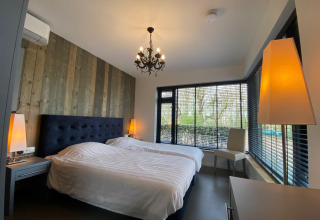 Dormitorio moderno en Nature House, Buitengoed Ruysbos, Países Bajos, con ventanas grandes y decoración de madera.