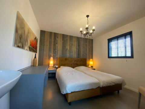 Dormitorio moderno en la cabaña Nature House, Buitengoed Ruysbos, con cama doble y pared de madera.