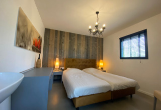 Modernes Schlafzimmer in der Nature House Lodge, Buitengoed Ruysbos, mit Doppelbett und Holzwand.