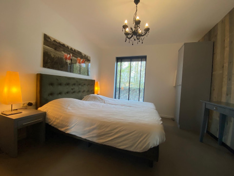 Slaapkamer met groot bed, warme verlichting en raam bij Nature House, Buitengoed Ruysbos, Nederland.