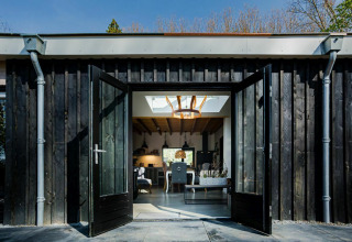 Portes doubles ouvertes d’un lodge Nature House à Buitengoed Ruysbos, Pays-Bas, montrant un intérieur moderne.