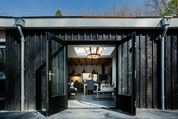 Dubbele deuren open van een natuurhuisje bij Buitengoed Ruysbos, Nederland, met zicht op modern interieur.