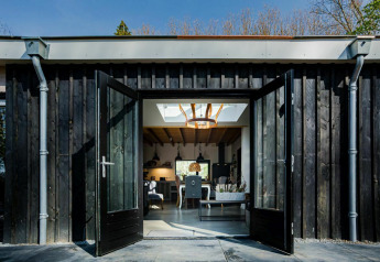 Portes doubles ouvertes d’un lodge Nature House à Buitengoed Ruysbos, Pays-Bas, montrant un intérieur moderne.