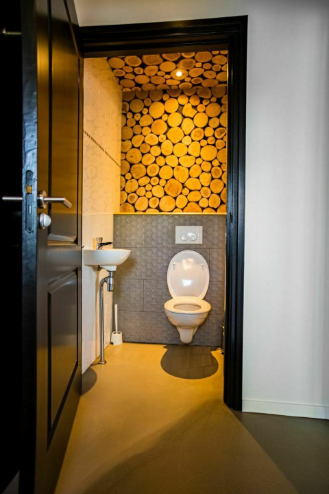 Baño moderno decorado con troncos en la pared en Nature House, Buitengoed Ruysbos, Países Bajos.