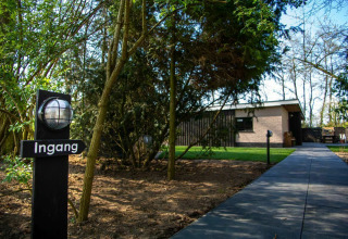 Entrance to a nature house lodge at Buitengoed Ruysbos in the Netherlands, with trees and pathway.