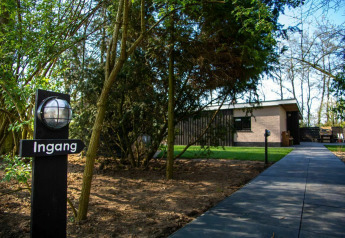 Entrée d'une maison nature à Buitengoed Ruysbos, Pays-Bas, entourée d'arbres et d'une allée pavée.