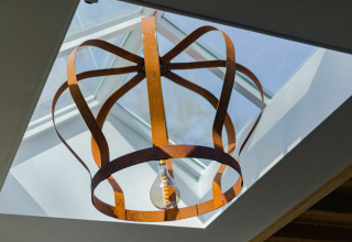 Artistiek metalen plafondlamp onder een dakraam in Nature House bij Buitengoed Ruysbos, Nederland.