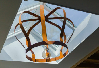Artistieke metalen plafondlamp onder een dakraam in Nature House bij Buitengoed Ruysbos, Nederland.