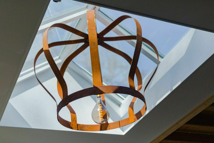 Artistiek metalen plafondlamp onder een dakraam in Nature House bij Buitengoed Ruysbos, Nederland.