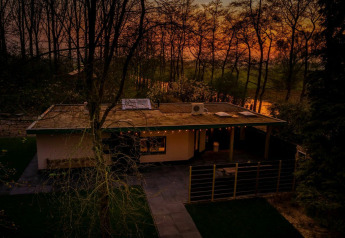 Nature House lodge bij Buitengoed Ruysbos, Nederland, omringd door bomen bij een prachtige zonsondergang.