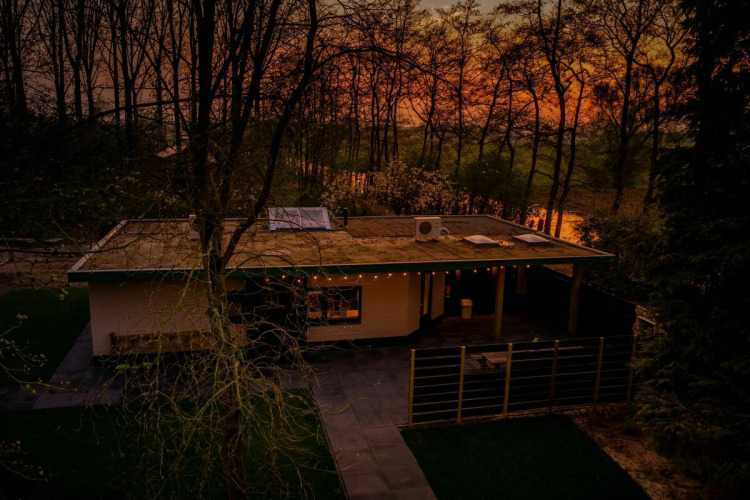Nature House lodge bij Buitengoed Ruysbos in Nederland, omgeven door bomen en natuur bij zonsondergang.