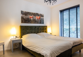 Dormitorio moderno en Nature House, Buitengoed Ruysbos, Países Bajos, con cama doble y cuadro de vacas.