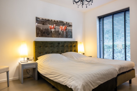 Modern bedroom at Nature House, Buitengoed Ruysbos, Netherlands, featuring a double bed and cow artwork.