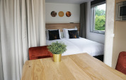 Accogliente interno tiny house all’Hotel Lodge di De Boshoek, Paesi Bassi, con letto matrimoniale e tavolo.