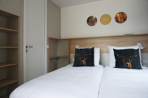 Modern tiny house hotel room at De Boshoek, Netherlands, featuring twin beds and deer-themed decor.