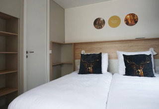 Modern tiny house hotel room at De Boshoek, Netherlands, featuring twin beds and deer-themed decor.