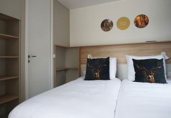 Chambre design au Tiny House Hotel Lodge à De Boshoek, Pays-Bas, avec lits jumeaux et coussins cerf.