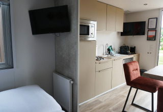 Photo of a tiny house with modern kitchen and bedroom at Hotel Lodge, Holiday park De Boshoek, Netherlands.