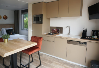 Tiny house hotel lodge keuken en eetgedeelte bij Vakantiepark De Boshoek, Nederland, modern ingericht.